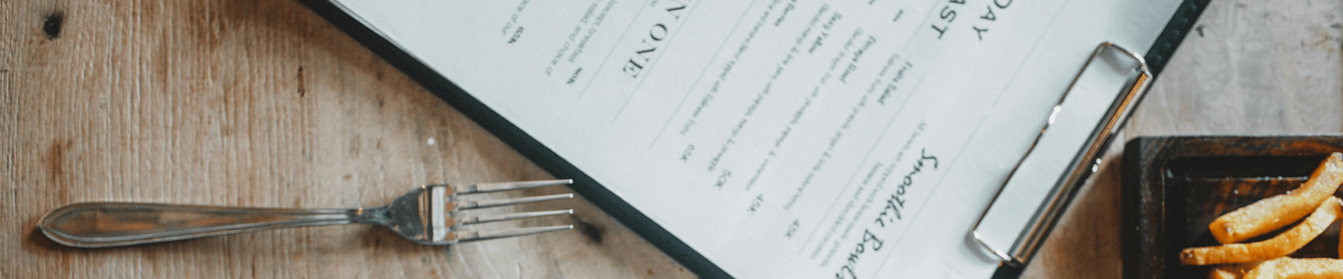Fork and french fries served on table in cafe with menu