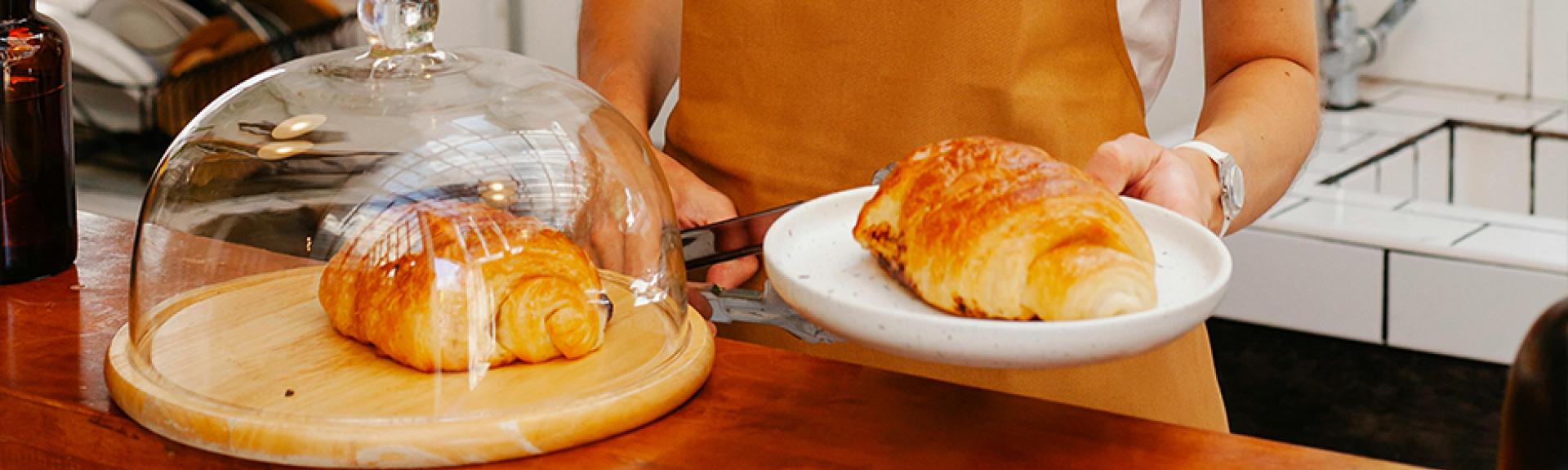 Restaurant worker serving croissant