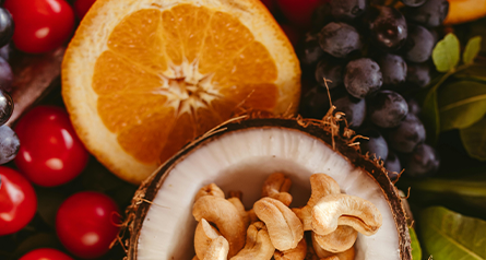 Cashews in a Halved Coconut surrounded by Tomatoes, Grapes and Citrus Fruits