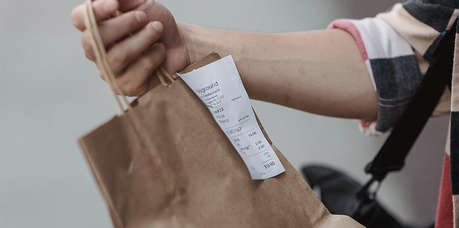 Person holding a bag with receipt attached