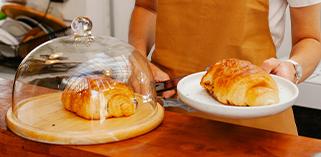 Restaurant worker serving a croissant 