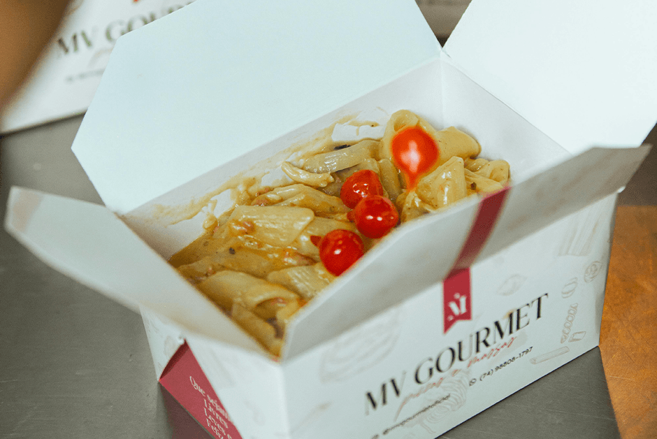 MV Gourmet takeout box with pasta and cherry tomatoes open on a kitchen counter.