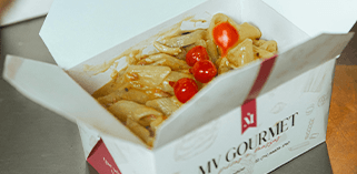 MV Gourmet takeout box with pasta and cherry tomatoes open on a kitchen counter.
