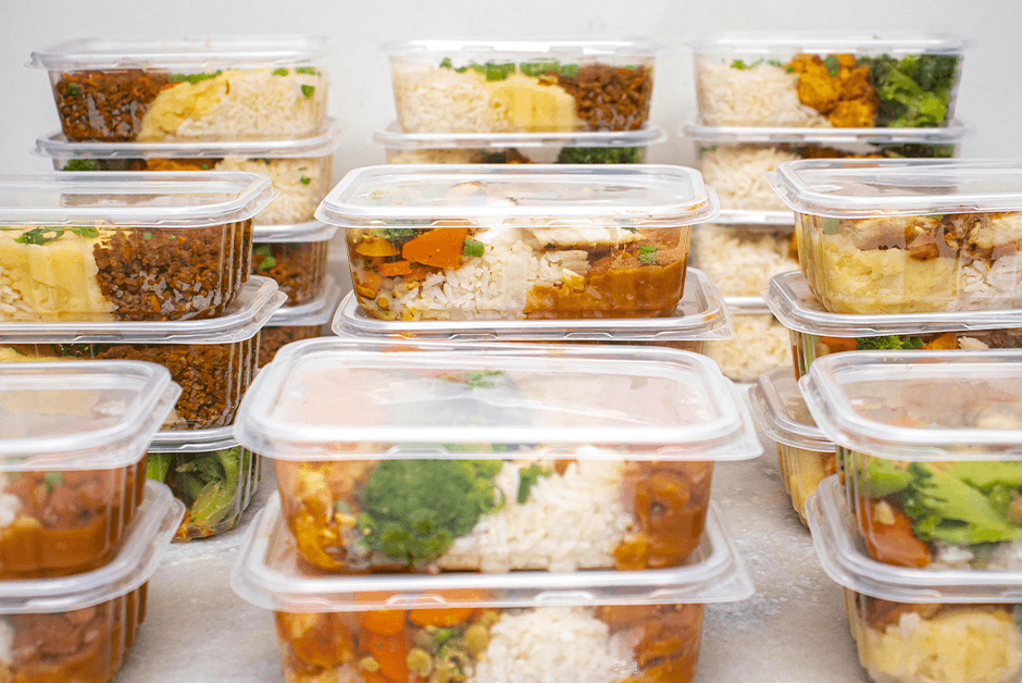 Multiple containers of prepared meals with rice and vegetables
