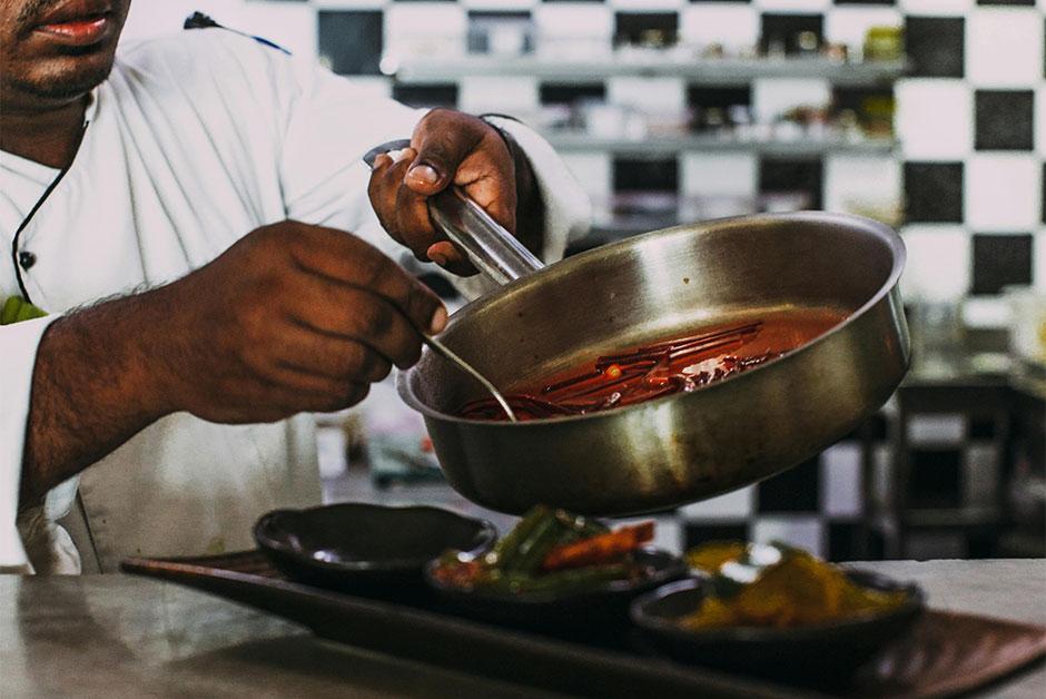 Chef pouring sauce over a dish