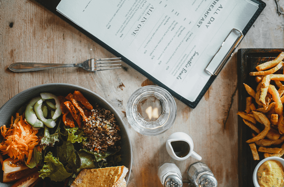 Salad bowl and french fries served on table in cafe