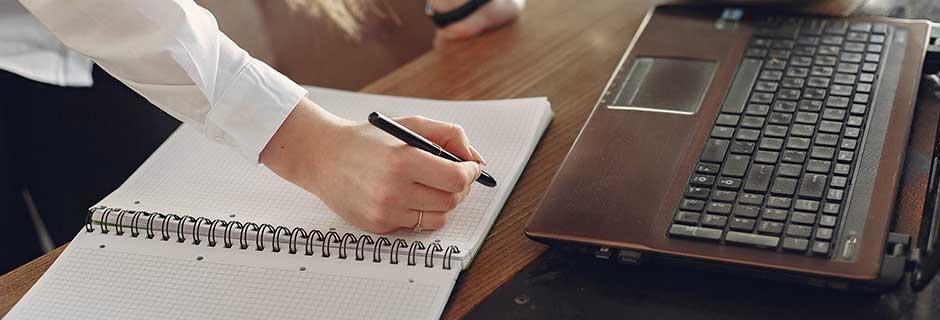 Person taking a training on a computer, writing on paper