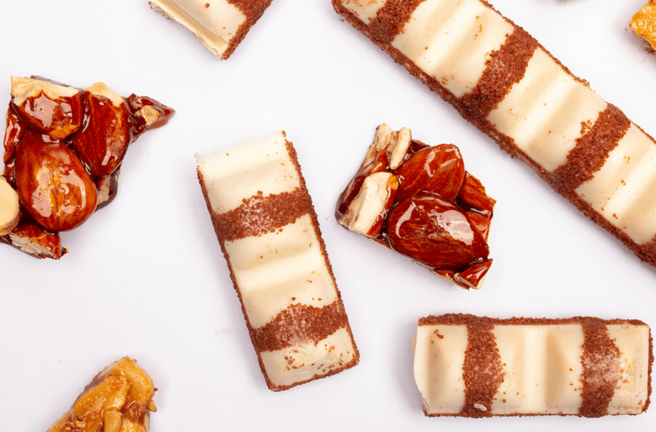 Delicious White Chocolate Bars and Glazed Nuts on White Surface